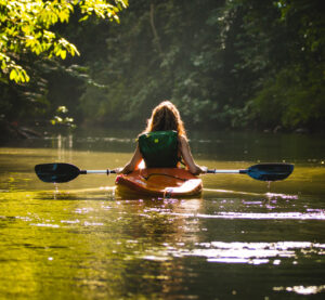 Woman kayaking across a calm river